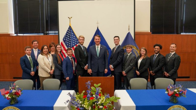 Fellows participants standing next to Glen Youngkin in conference room